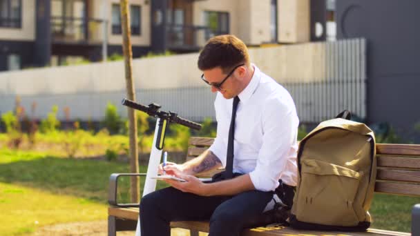 Επιχειρηματίας γράφοντας στο σημειωματάριο και πίνοντας καφέ — Αρχείο Βίντεο