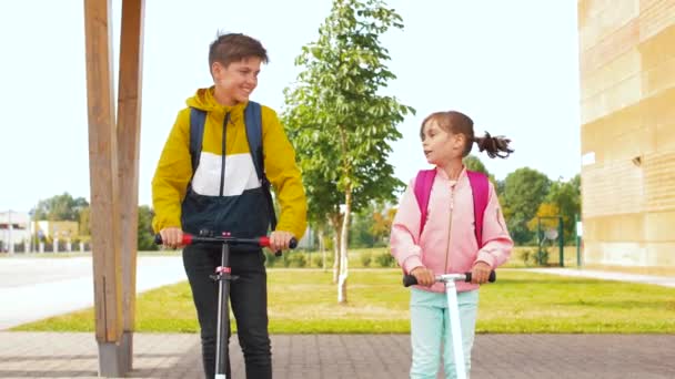 Šťastné školní děti jízda na skútrech — Stock video