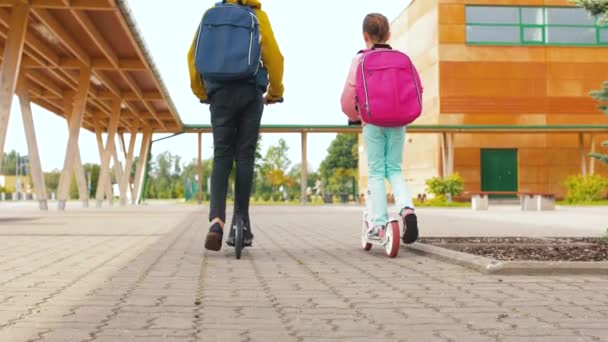 Crianças da escola com mochilas montando scooters — Vídeo de Stock