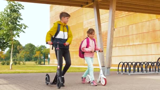 バックパックやスクーターを持つ幸せな学校の子供たち — ストック動画