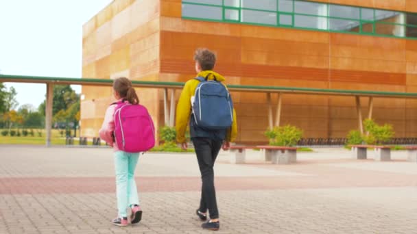 Kinderen met rugzakken lopen van school — Stockvideo