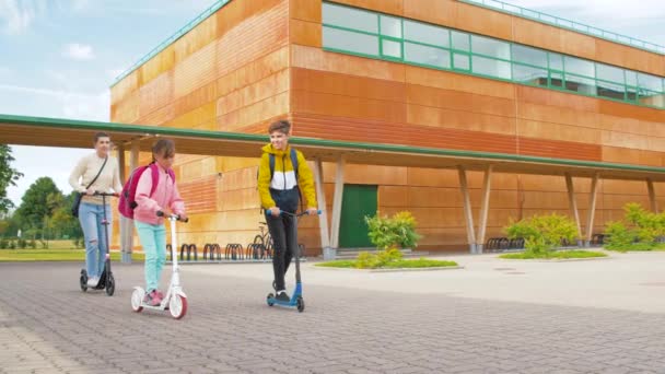 Gelukkig schoolkinderen met moeder paardrijden scooters — Stockvideo