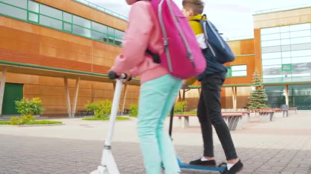 Crianças da escola feliz com scooters mãe equitação — Vídeo de Stock