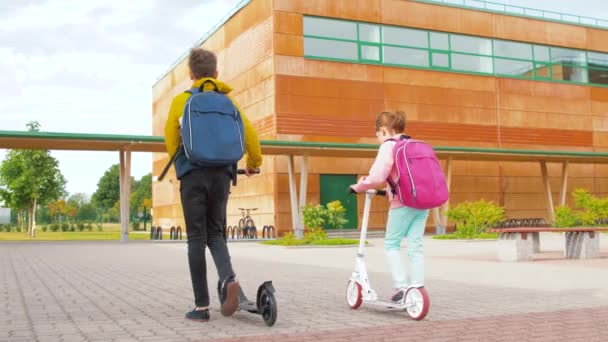 Crianças da escola feliz com mochilas e scooters — Vídeo de Stock