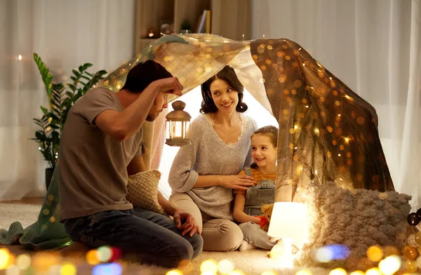 Famiglia felice che gioca nella tenda dei bambini di notte a casa — Foto Stock