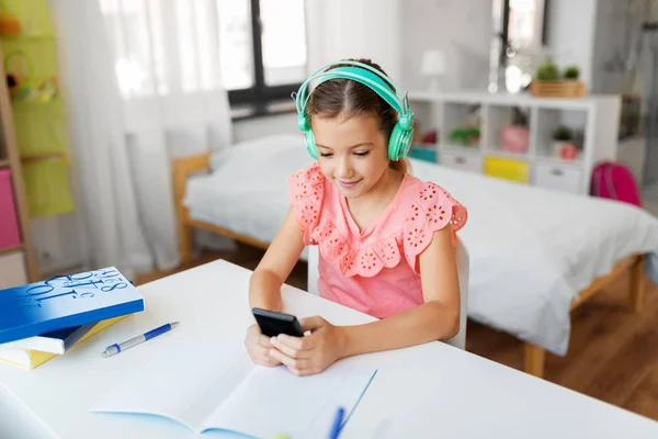 Девушка в наушниках слушает музыку по мобильному телефону — стоковое фото