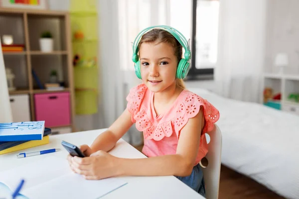 Dívka ve sluchátkách naslouchající hudbě na mobilu — Stock fotografie