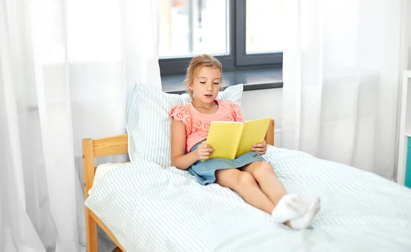 Menina feliz leitura livro em casa — Fotografia de Stock