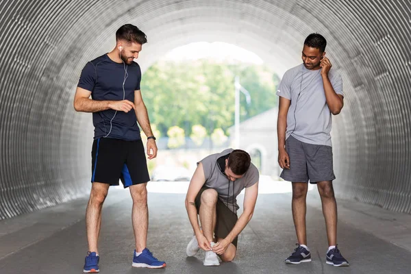 Male friends with earphones training outdoors — Stock Photo, Image