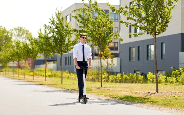 Jovem empresário montando scooter elétrico ao ar livre — Fotografia de Stock