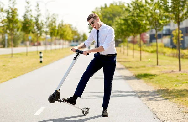 Ung forretningsmann som kjører elektrisk scooter utendørs – stockfoto