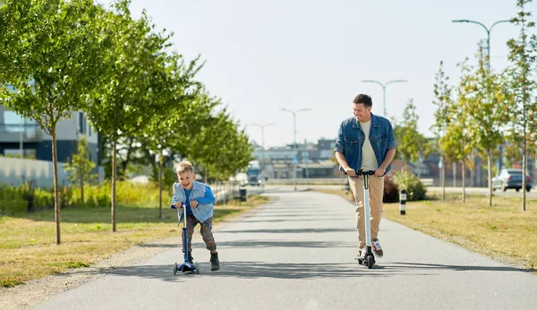 Vater und kleiner Sohn fahren Roller in der Stadt — Stockfoto