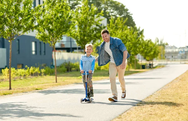 Glücklicher Vater und kleiner Sohn fahren Roller in der Stadt — Stockfoto