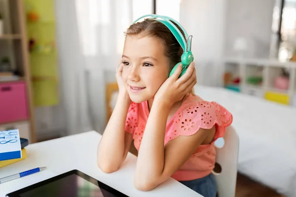 Evde tablet bilgisayarlı kulaklıklı bir kız. — Stok fotoğraf