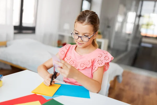 Mädchen schneidet zu Hause Farbpapier mit der Schere — Stockfoto