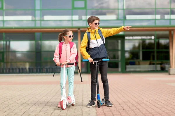 Gelukkige schoolkinderen met rugzakken en scooters — Stockfoto