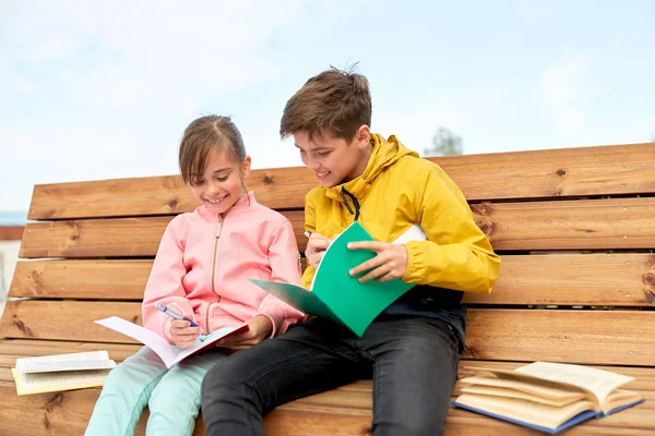 School children with notebooks sitting on bench — Stock Photo, Image