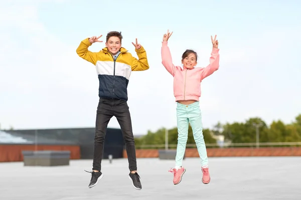 Enfants heureux sautant sur le toit et montrant la paix — Photo