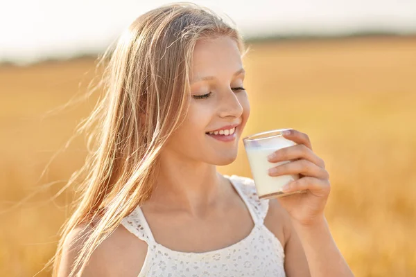 Девушка пьет молоко из стекла на зерновом поле — стоковое фото