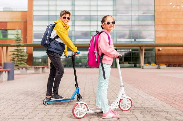 Niños de la escuela con mochilas a caballo scooters —  Fotos de Stock