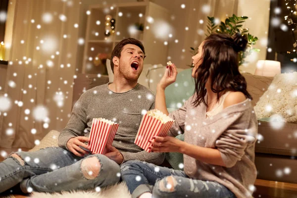 Feliz pareja comiendo palomitas de maíz en casa —  Fotos de Stock