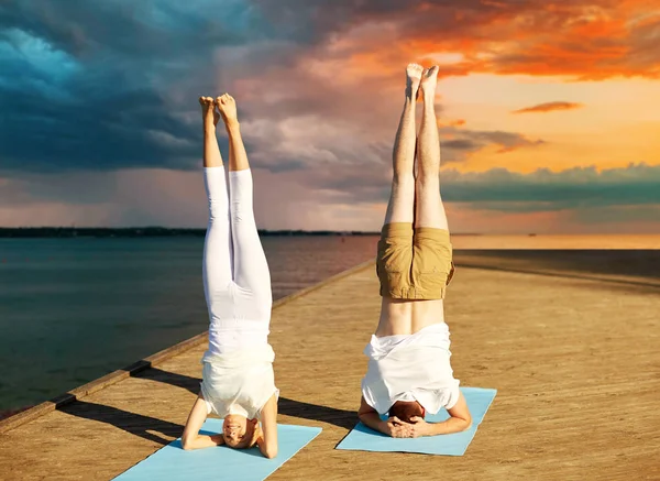 Pareja haciendo yoga headstand en estera al aire libre —  Fotos de Stock