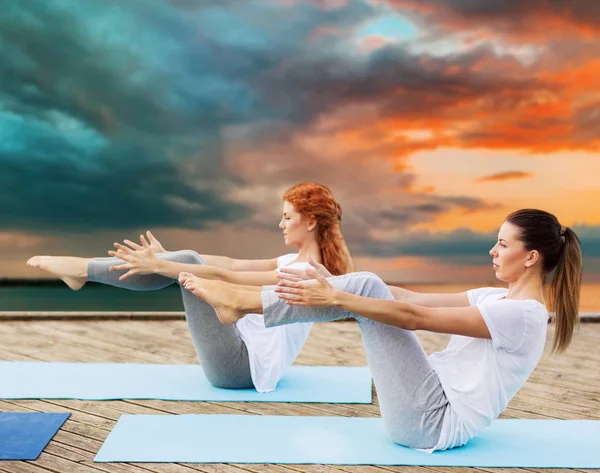 Kvinnor gör yoga i halv-boat pose utomhus — Stockfoto