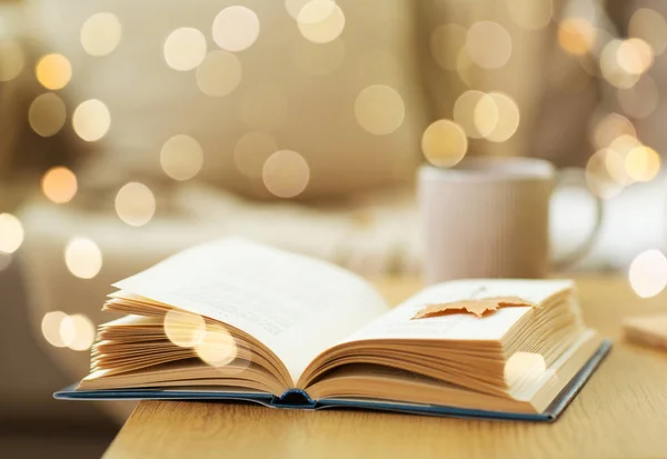 Libro con hoja de otoño en mesa de madera en casa — Foto de Stock