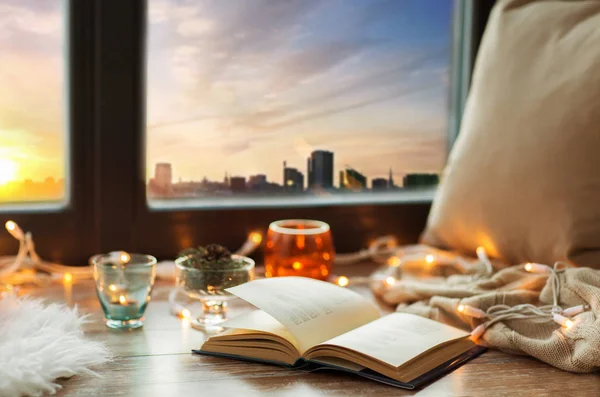 Libro, luces de guirnalda y velas en el alféizar de la ventana — Foto de Stock