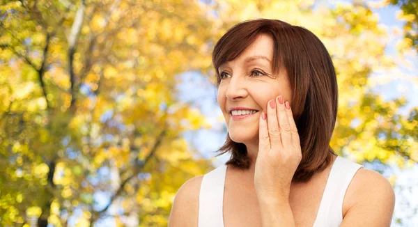 Portrait de femme âgée souriante touchant son visage — Photo