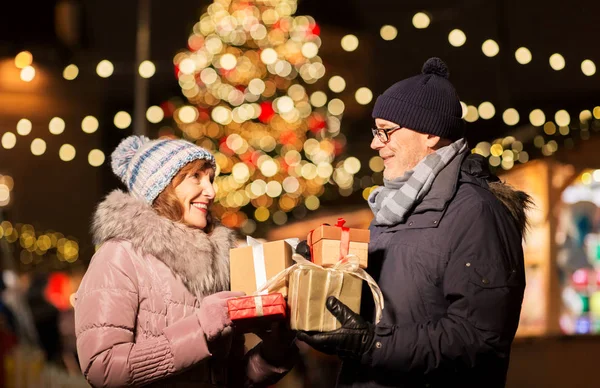 Glückliches Seniorenpaar mit Geschenk auf Weihnachtsmarkt — Stockfoto