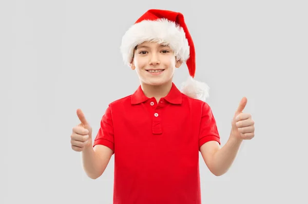 Sourire garçon dans santa helper chapeau montrant pouces vers le haut — Photo