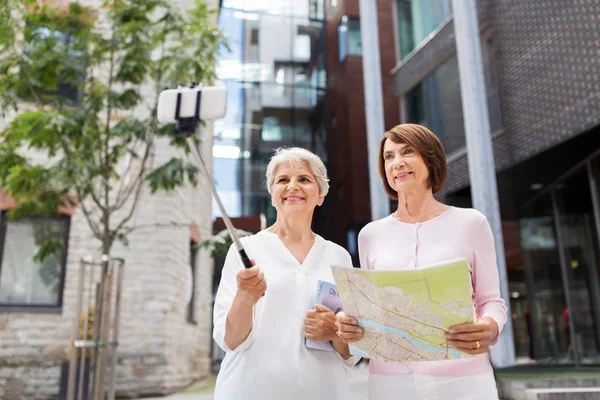 Ανώτερες γυναίκες με χάρτη και τον οδηγό της πόλης λήψη selfie — Φωτογραφία Αρχείου