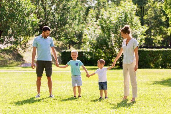 Família feliz de mãos dadas no parque de verão — Fotografia de Stock