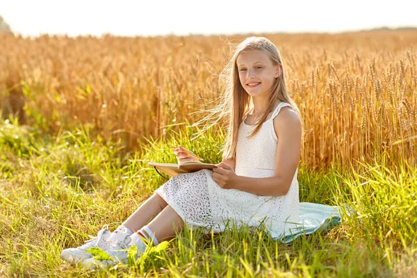 Chica sonriente escribiendo a diario en el campo de cereales — Foto de Stock