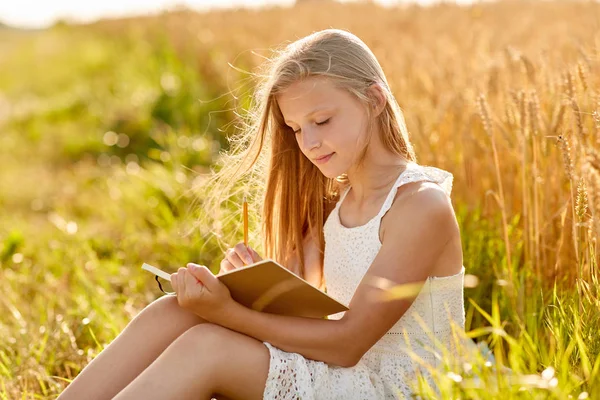 Usmívající se holčička, která psala do deníku na poli cereálie — Stock fotografie