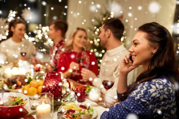 Woman calling on smartphone at christmas dinner — Stock Photo, Image