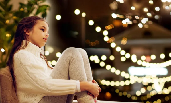 Sad girl sitting at home window on christmas — Stock Photo, Image