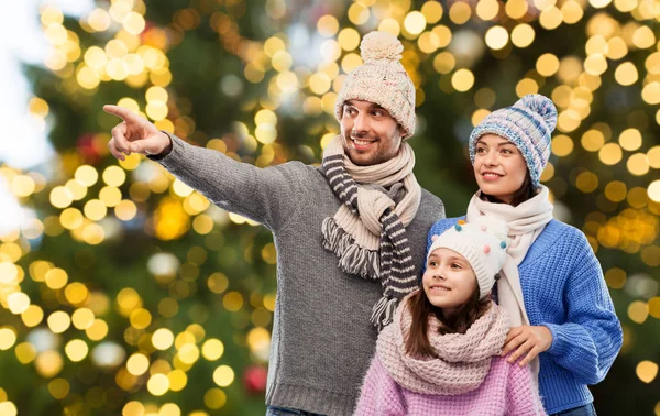 Happy family in winter hats over christmas lights — Stock Photo, Image