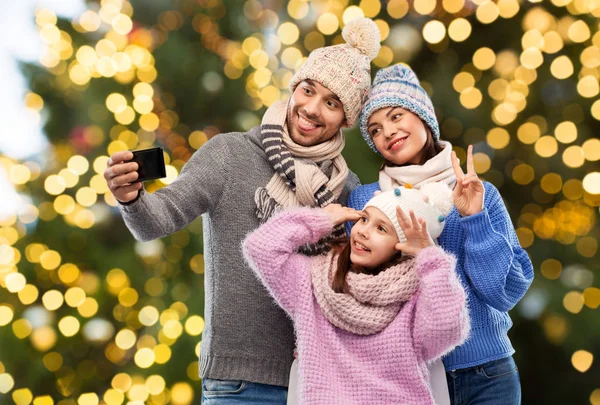 Familia feliz tomando selfie sobre luces de Navidad — Foto de Stock