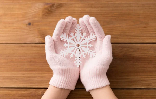 Händer i ljusrosa handskar som håller stor snöflinga — Stockfoto