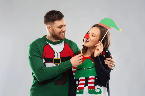Пара с рождественским реквизитом в уродливых свитерах — стоковое фото