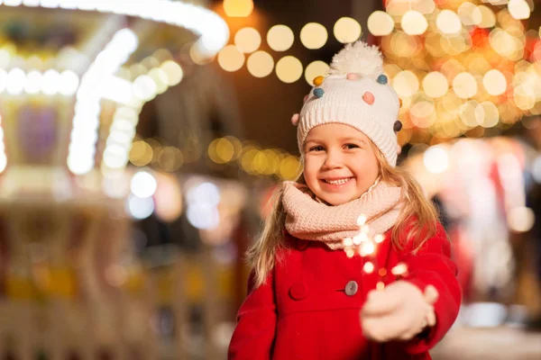 Menina feliz com sparkler no mercado de natal — Fotografia de Stock