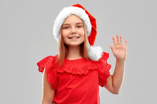 Smiling girl in snata helper hat waving hand — Stock Photo, Image