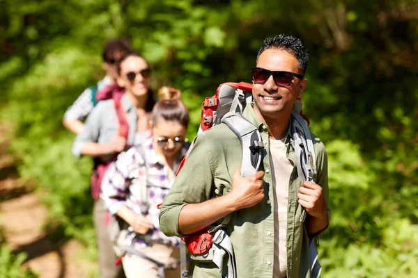 Group of friends with backpacks hiking in forest — Stock Photo, Image