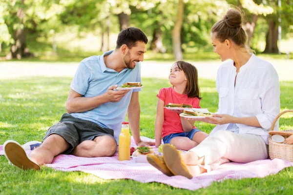 Familia feliz teniendo un picnic en el parque de verano — Foto de Stock