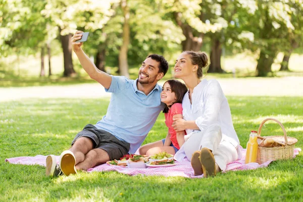 Семья устраивает пикник и делает селфи в парке — стоковое фото