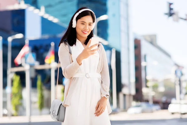 Asiatisk kvinna med smartphone och hörlurar i City — Stockfoto