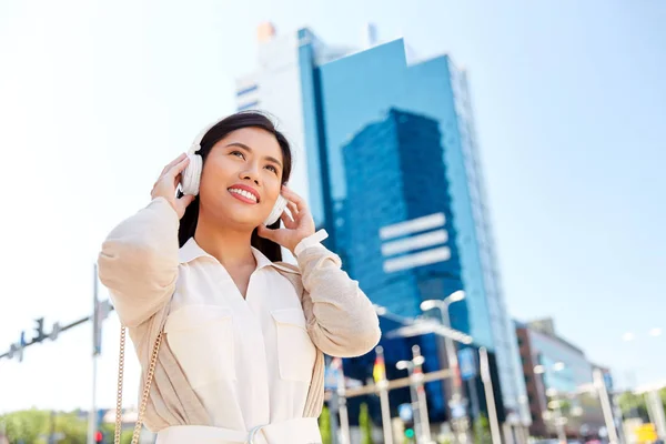 Feliz sorrindo asiático mulher com fones de ouvido na cidade — Fotografia de Stock