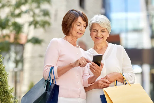 Gamla kvinnor med shoppingväskor och mobiltelefon i City — Stockfoto